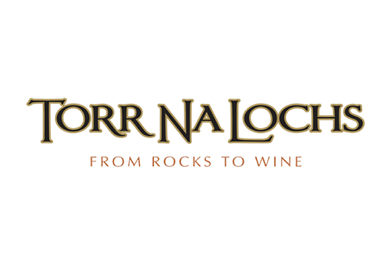 Logo for Torr Na Lochs Vineyard with the tagline FROM ROCKS TO WINE in capital letters. The main text is gold with a black outline; the tagline appears in a smaller, copper-colored font below.