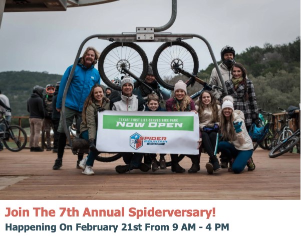A group of people pose smiling by a ski lift holding a banner that reads Texas First Lift-Served Bike Park - NOW OPEN - Spider Mountain. Mountain bikes and hills are in the background.