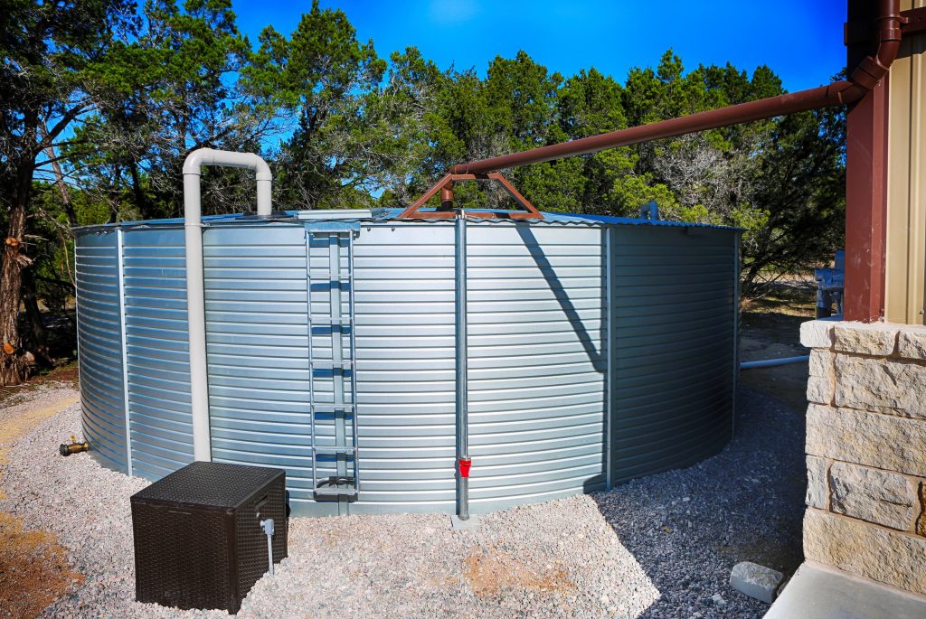Large corrugated steel water storage cistern with rainwater collection system on a Texas Hill Country property